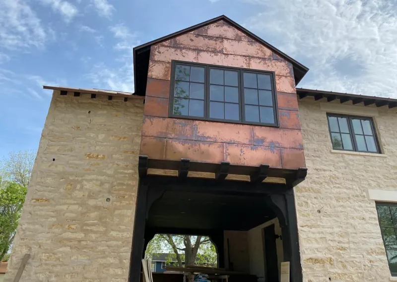 Copper metal panel facade on a stone building for Skylight Installation in Country Homes