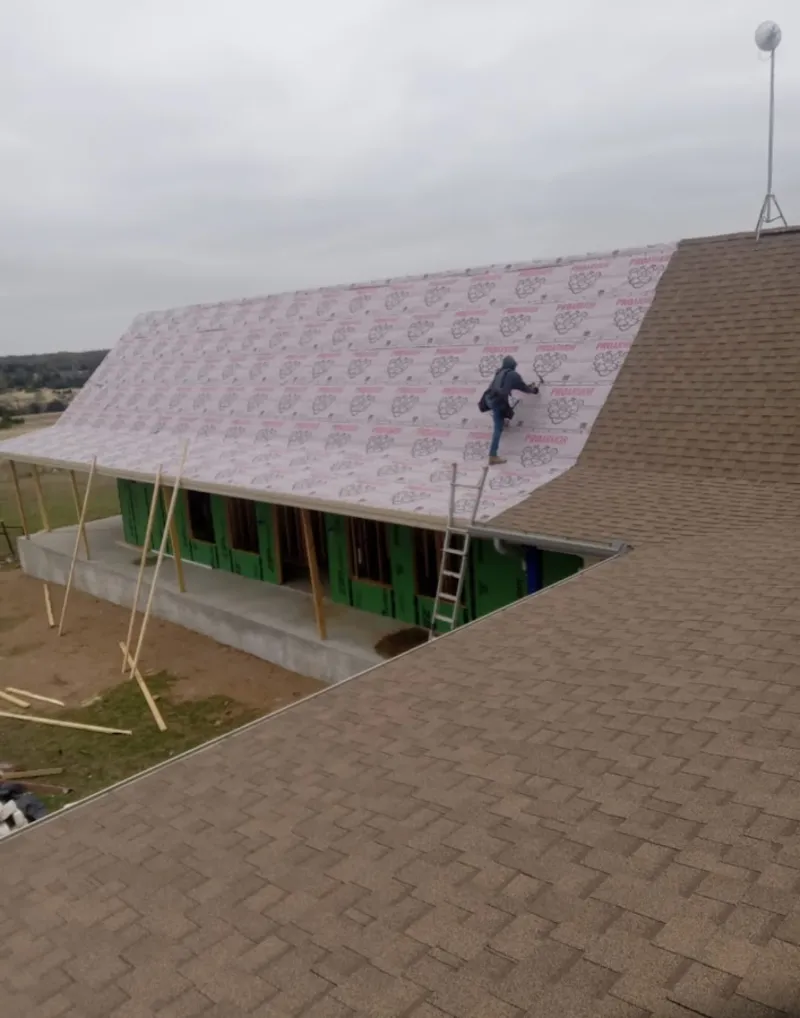 Worker preparing underlayment for a metal roof installation in Country Homes